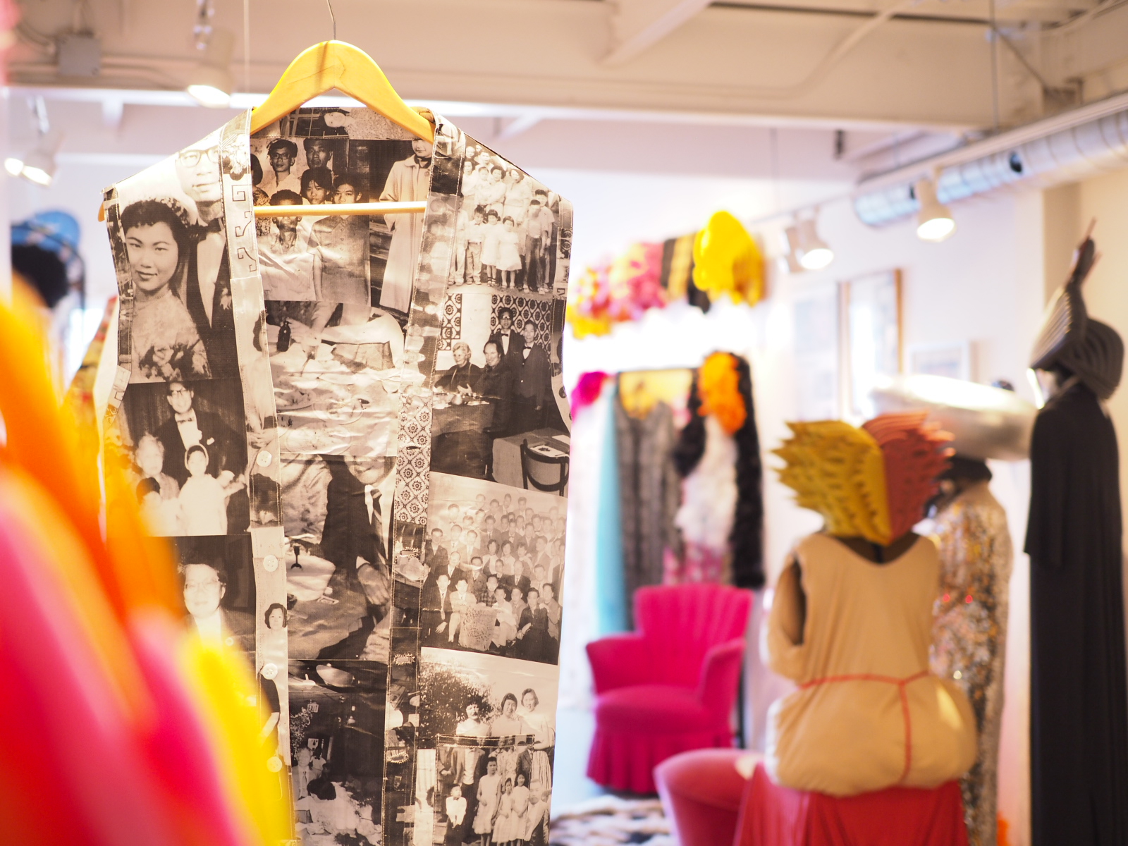 Invisible Identities: a waiter's vest made out of paper with black and white Kwan family photos hangs among colour clothing and artifacts from China Doll's apartment
