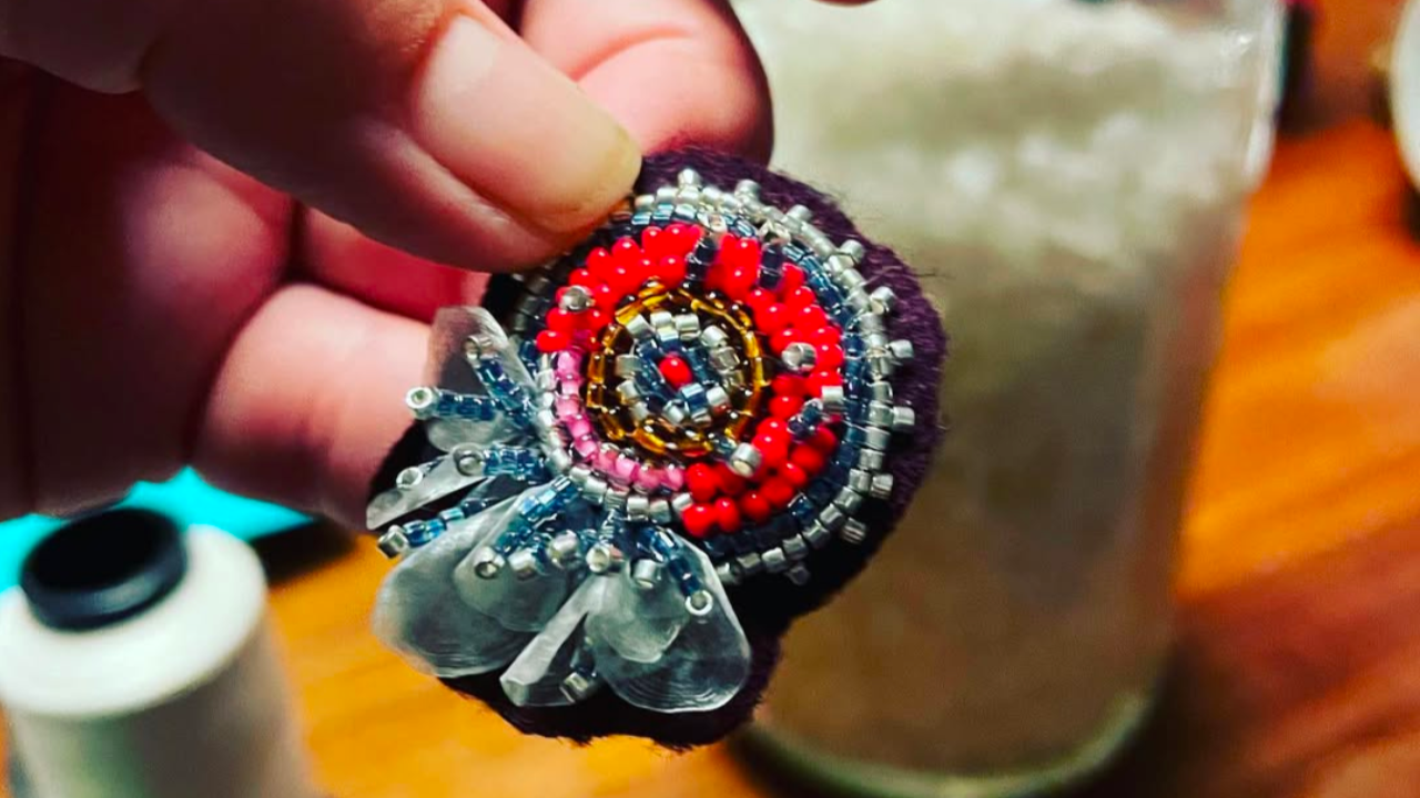 Jaime Morse holds a finished piece made of beads and fish scales